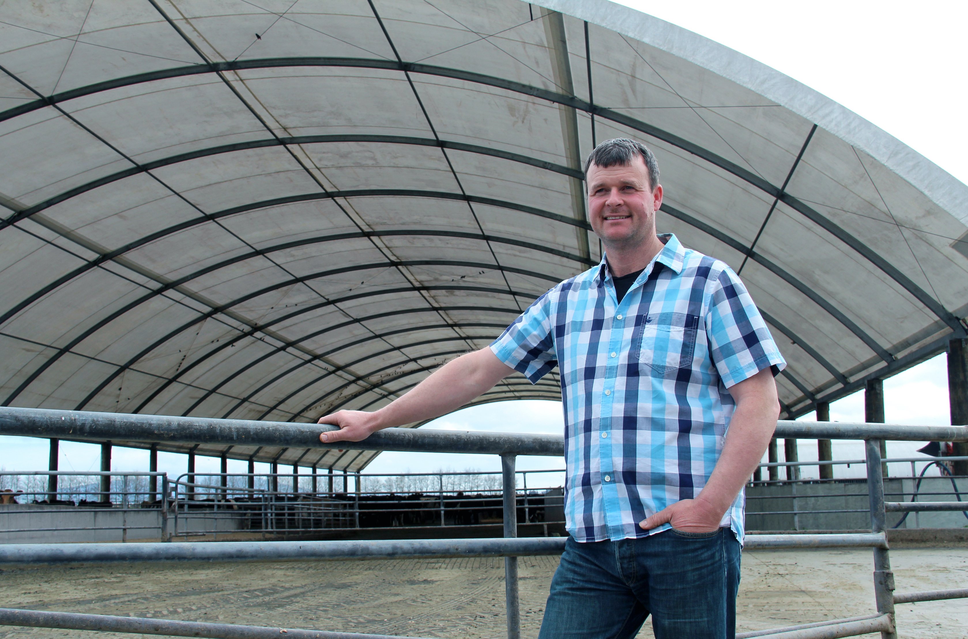 man standing in front of farm building